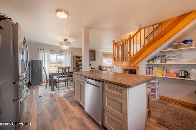 kitchen with stainless steel appliances, wood counters, wood finished floors, open shelves, and a kitchen breakfast bar