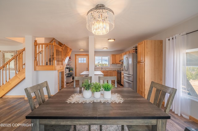 dining room featuring stairs, a chandelier, wood finished floors, and baseboards