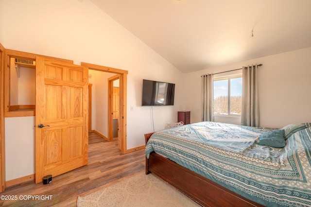 bedroom with light wood-style floors, baseboards, and high vaulted ceiling
