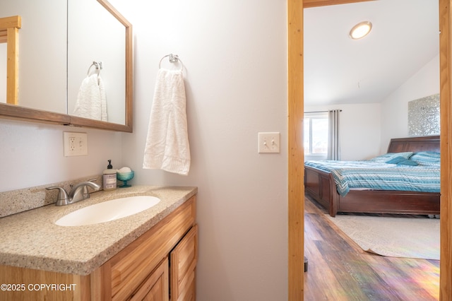 bathroom featuring wood finished floors, vanity, and lofted ceiling