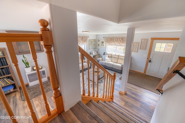 stairway with wood finished floors, plenty of natural light, and baseboards