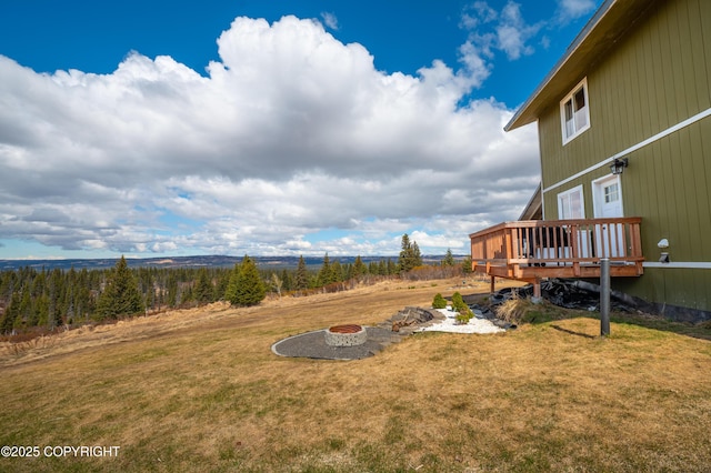 view of grassy yard featuring an outdoor fire pit and a deck
