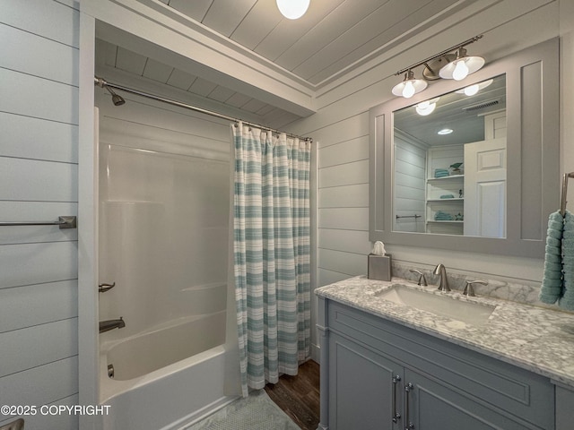 full bathroom with visible vents, wood walls, wood finished floors, shower / tub combo, and vanity