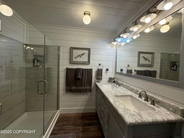 bathroom featuring double vanity, a sink, wood finished floors, and a shower stall