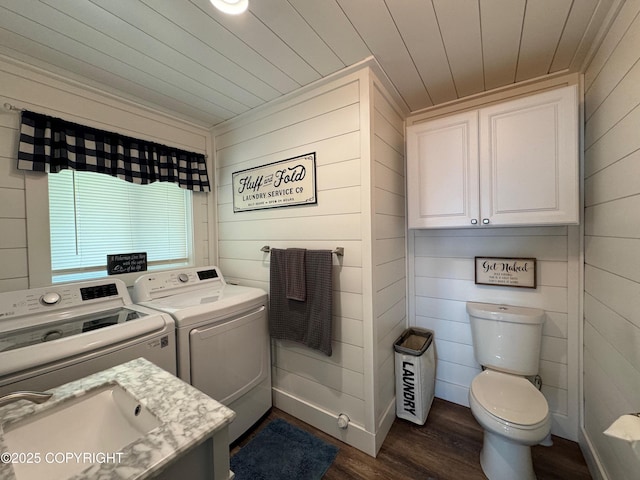 washroom featuring laundry area, wood walls, dark wood-style flooring, a sink, and independent washer and dryer
