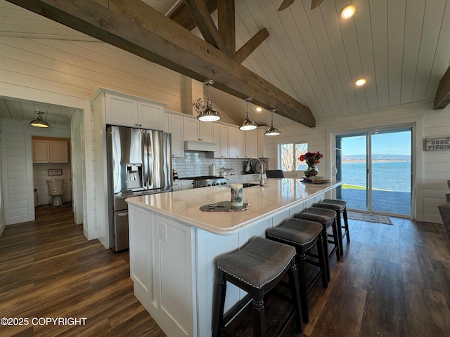 kitchen with a sink, stainless steel fridge with ice dispenser, vaulted ceiling with beams, white cabinetry, and dark wood-type flooring