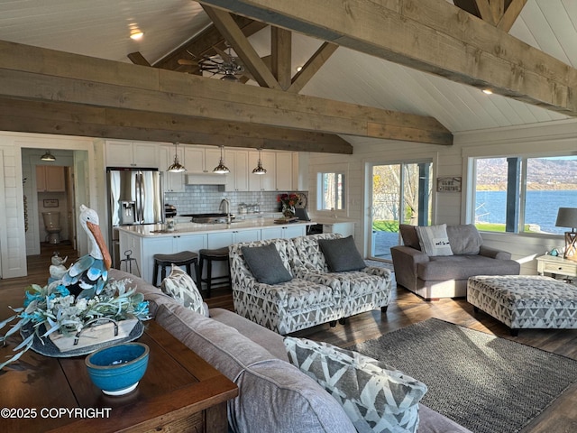 living room with plenty of natural light, lofted ceiling with beams, ceiling fan, and dark wood-type flooring