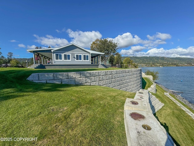 back of property featuring a lawn and a water view