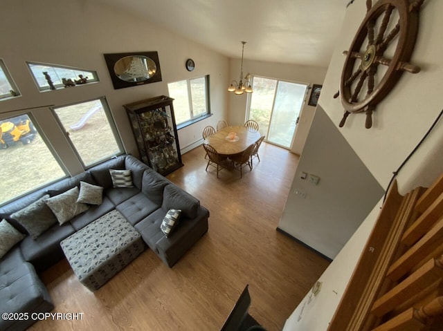 living room featuring baseboard heating, a chandelier, wood finished floors, and vaulted ceiling