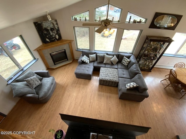 living area featuring ceiling fan, baseboard heating, a fireplace, wood finished floors, and vaulted ceiling