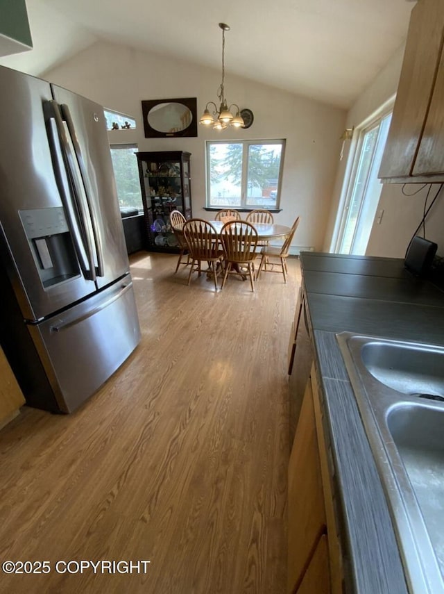 kitchen with wood finished floors, vaulted ceiling, a wealth of natural light, and stainless steel fridge with ice dispenser