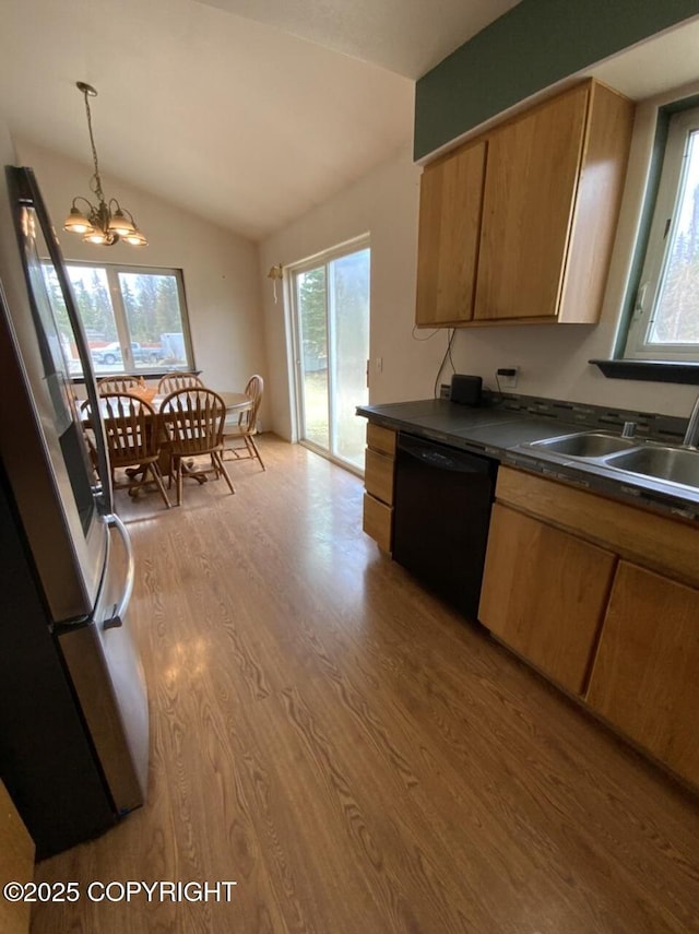 kitchen featuring dark countertops, a sink, black dishwasher, freestanding refrigerator, and wood finished floors