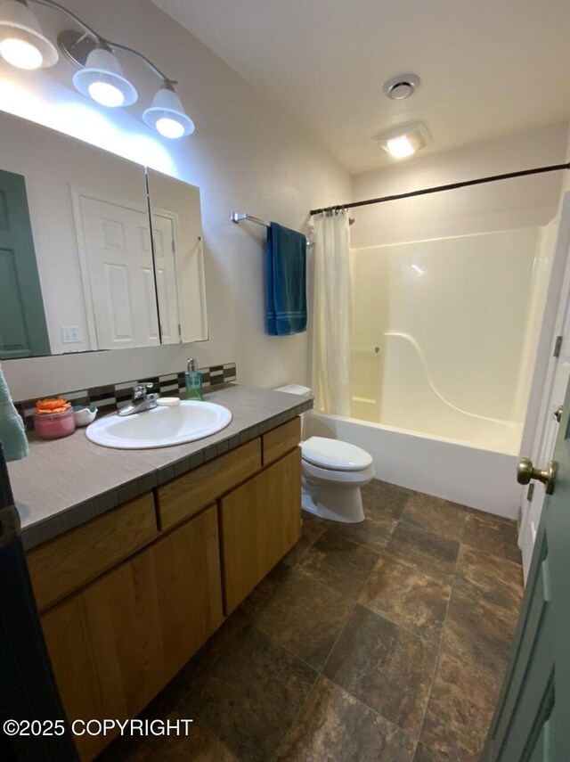 full bathroom featuring toilet, shower / bathtub combination with curtain, stone finish floor, and vanity