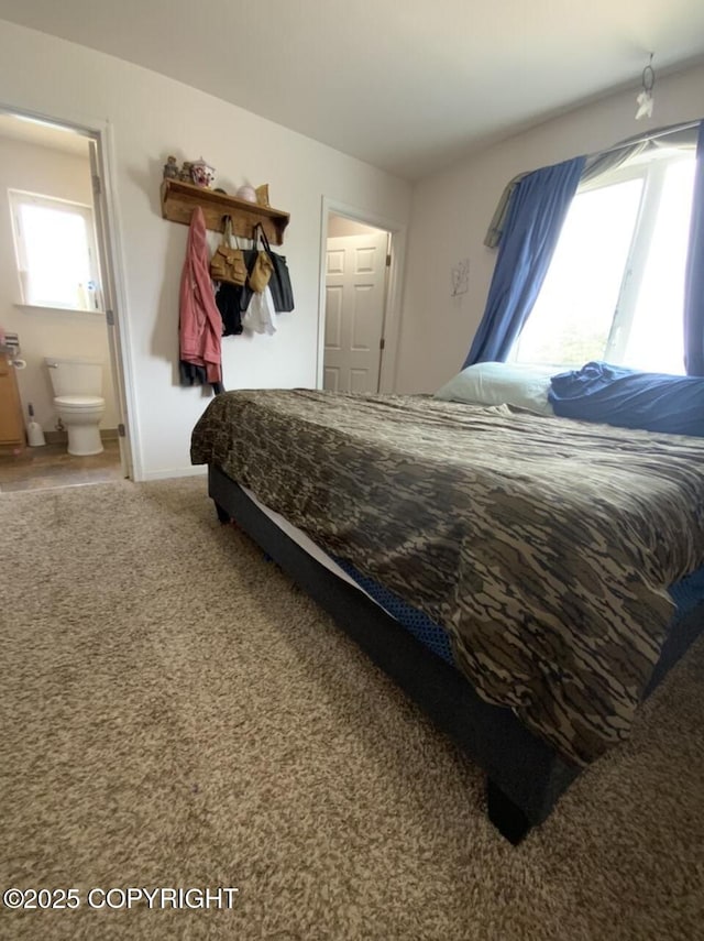 carpeted bedroom with connected bathroom and baseboards