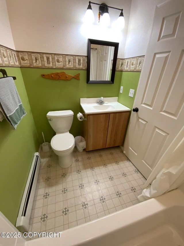bathroom with toilet, baseboards, baseboard heating, and vanity