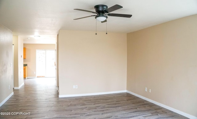 empty room featuring a ceiling fan, baseboards, and wood finished floors