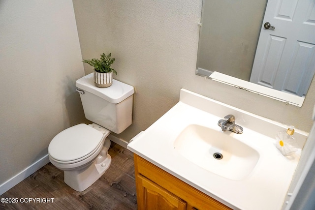 bathroom featuring toilet, baseboards, vanity, and wood finished floors