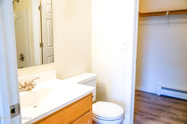 bathroom with toilet, a shower, wood finished floors, vanity, and a baseboard radiator