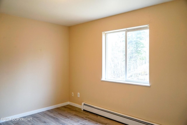empty room featuring a wealth of natural light, baseboards, wood finished floors, and a baseboard radiator