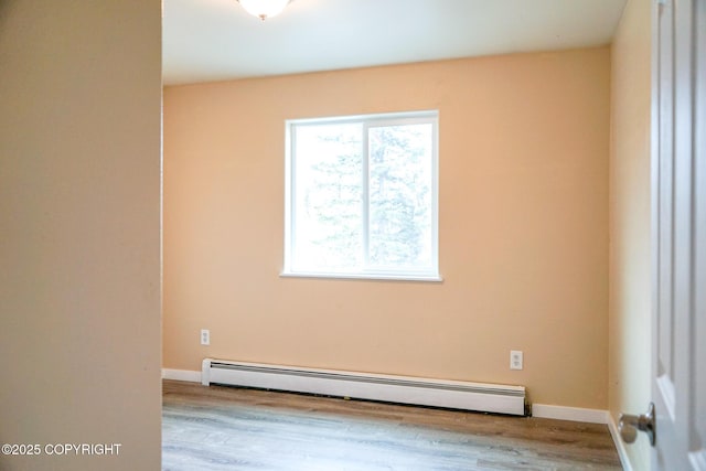 unfurnished room featuring baseboards, baseboard heating, and wood finished floors