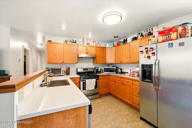 kitchen featuring a sink, a peninsula, stainless steel appliances, under cabinet range hood, and light countertops