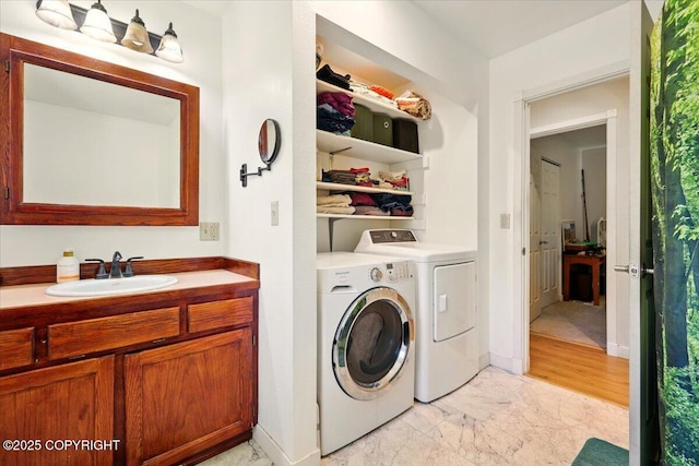 laundry room featuring a sink, independent washer and dryer, and marble finish floor