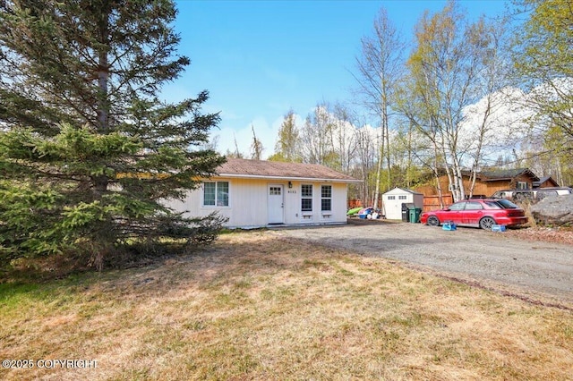 view of front of home with an outbuilding, a front yard, and a shed