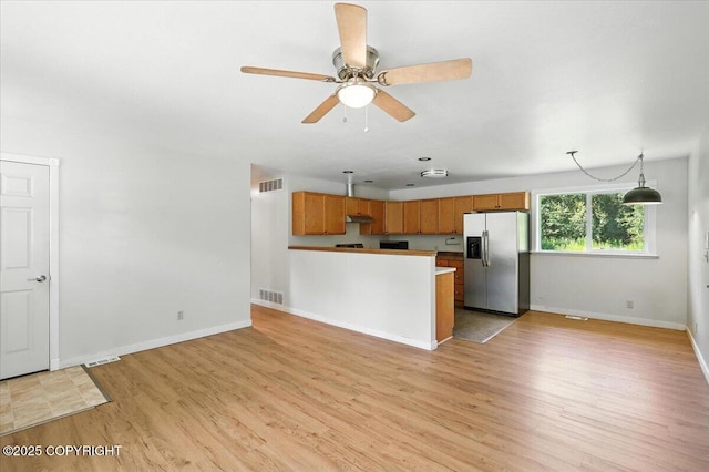 6132 S Northern Lights St, Wasilla, AK 99623 - kitchen with stainless steel fridge, light wood finished floors, ceiling fan, a peninsula, and brown cabinets