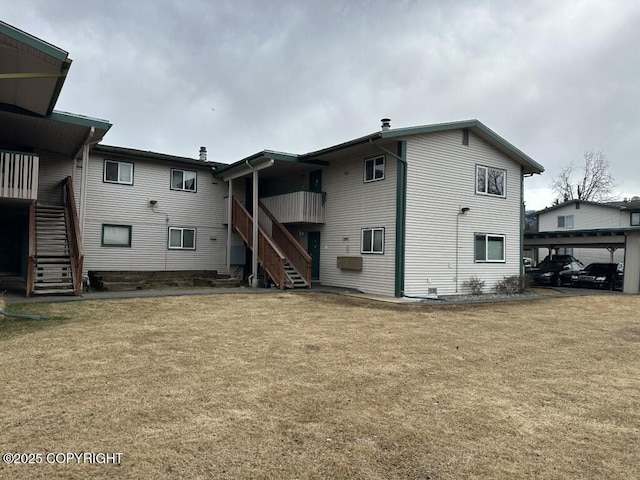 rear view of property featuring a yard and stairway