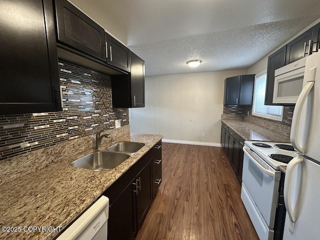 kitchen with decorative backsplash, white appliances, baseboards, dark wood-style floors, and a sink