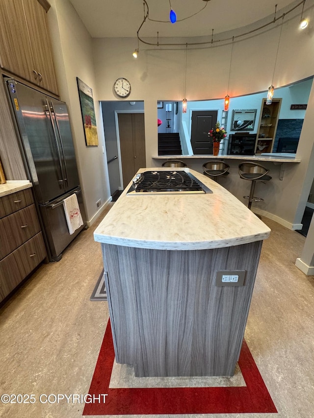 kitchen with a kitchen island, pendant lighting, light countertops, baseboards, and stainless steel appliances