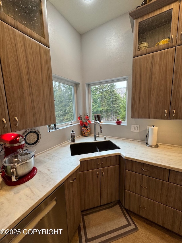 kitchen with a sink, glass insert cabinets, and light countertops