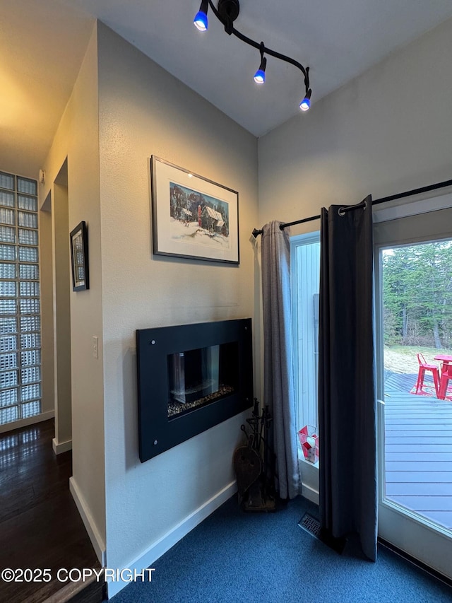 interior space with a glass covered fireplace and baseboards