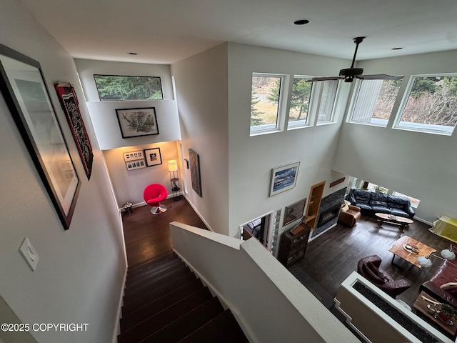 stairway with a ceiling fan, baseboards, recessed lighting, and wood finished floors