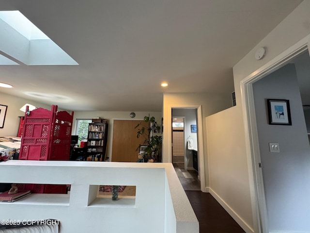 interior space with a skylight, baseboards, recessed lighting, and dark wood-type flooring