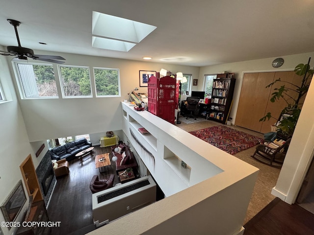 interior space featuring a skylight, a ceiling fan, and wood finished floors