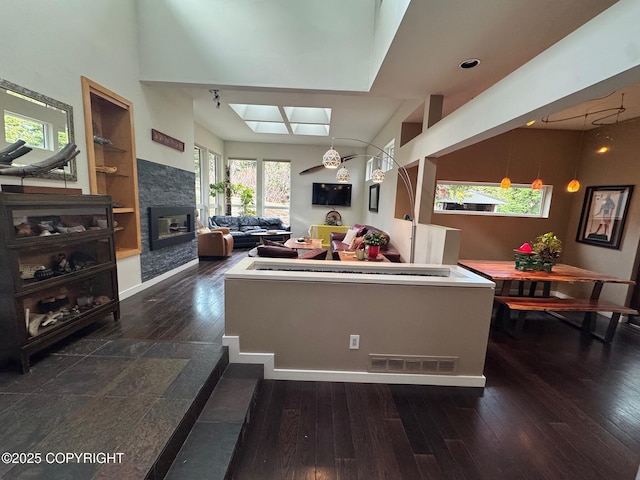 living room featuring visible vents, a skylight, hardwood / wood-style floors, and a stone fireplace