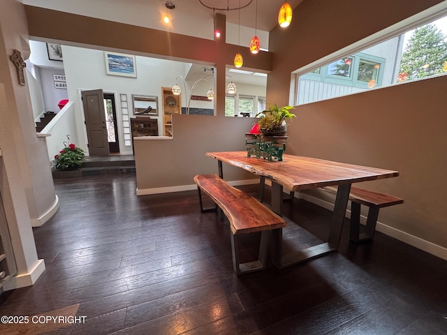 dining area featuring wood-type flooring, a high ceiling, baseboards, and stairs