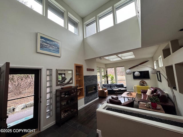 living room with a towering ceiling, a glass covered fireplace, and a wealth of natural light