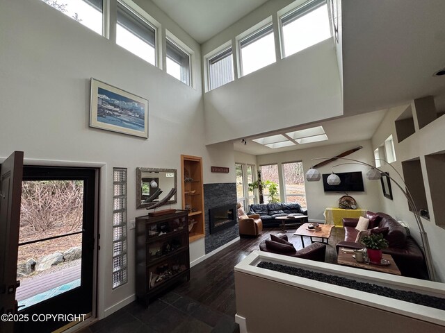 7041 Potter Hts, Anchorage, AK 99516 - living room featuring dark wood-style flooring, a glass covered fireplace, a wealth of natural light, and a towering ceiling