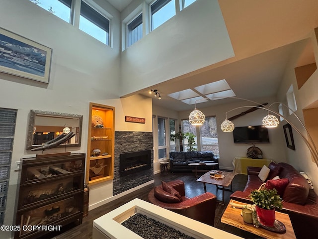 living room featuring a towering ceiling, dark wood-style flooring, a wealth of natural light, and a fireplace