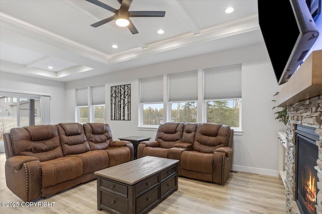 living area featuring a stone fireplace, plenty of natural light, ceiling fan, and light wood-type flooring