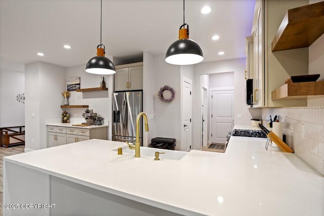 kitchen featuring stainless steel refrigerator with ice dispenser, open shelves, hanging light fixtures, and light countertops