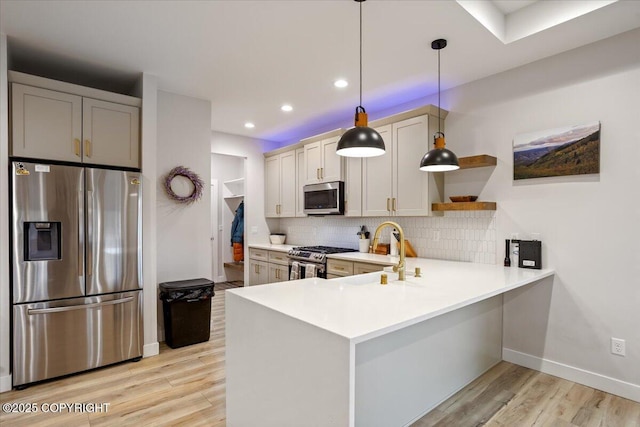 kitchen with open shelves, a peninsula, light wood-type flooring, light countertops, and appliances with stainless steel finishes