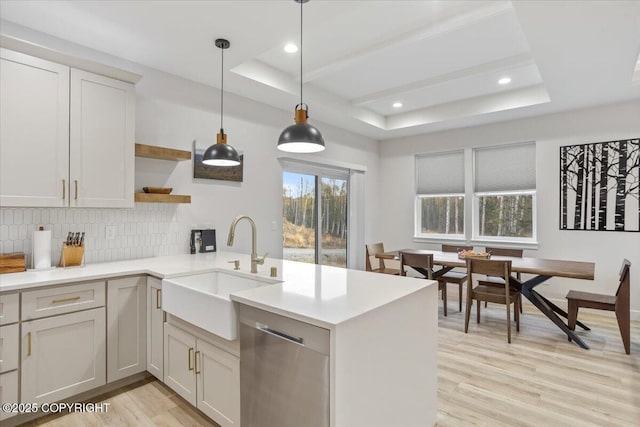 kitchen with tasteful backsplash, open shelves, dishwasher, a sink, and a tray ceiling
