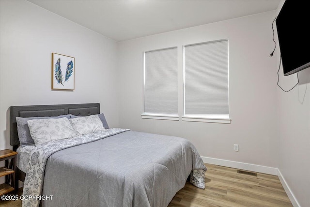 bedroom featuring baseboards, visible vents, and wood finished floors
