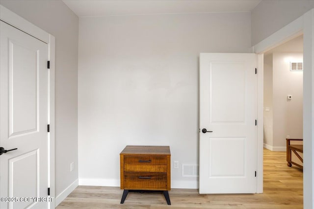 interior space with baseboards, light wood-style flooring, and visible vents