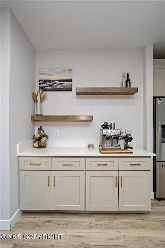 bar featuring stainless steel fridge and light wood-type flooring