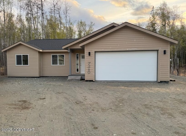 single story home featuring dirt driveway and a garage