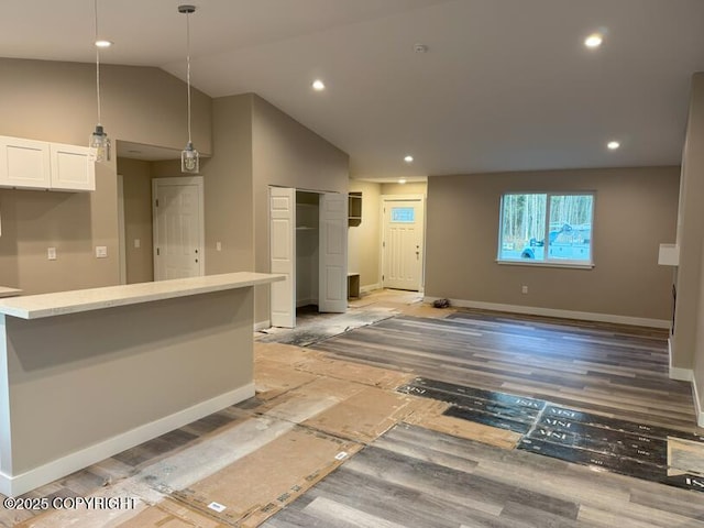 kitchen featuring white cabinets, baseboards, vaulted ceiling, light countertops, and decorative light fixtures